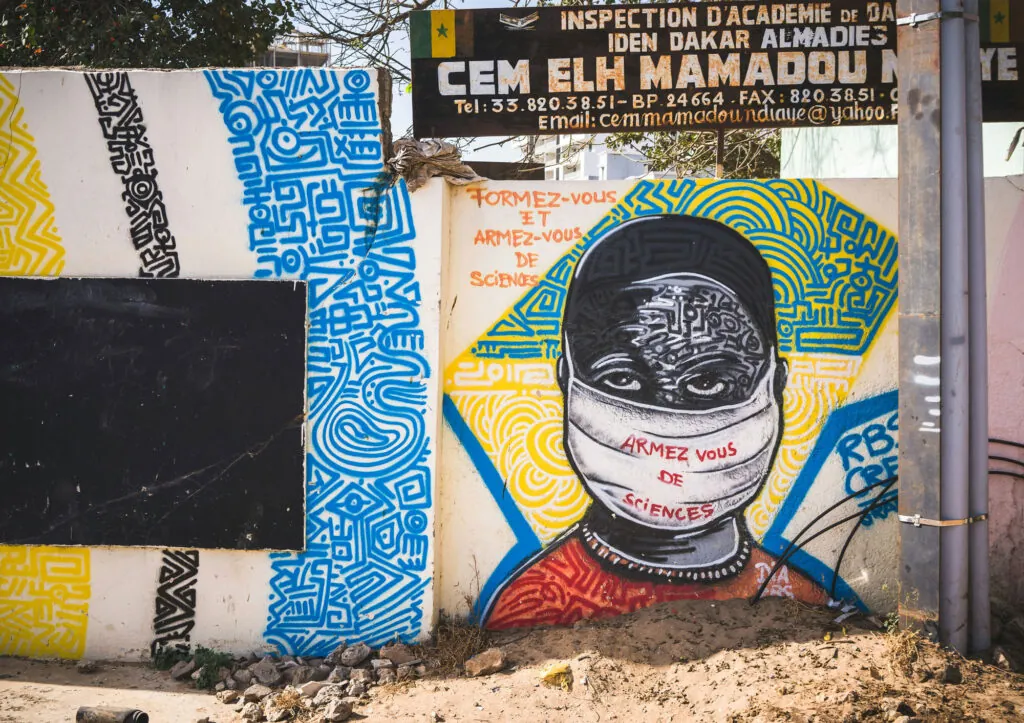 A wall with a painting of a young person wearing a mask