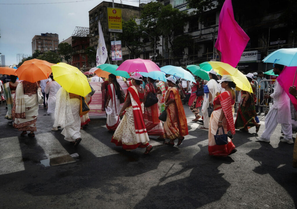 A group of people walking down a street holding colourful umbrellas