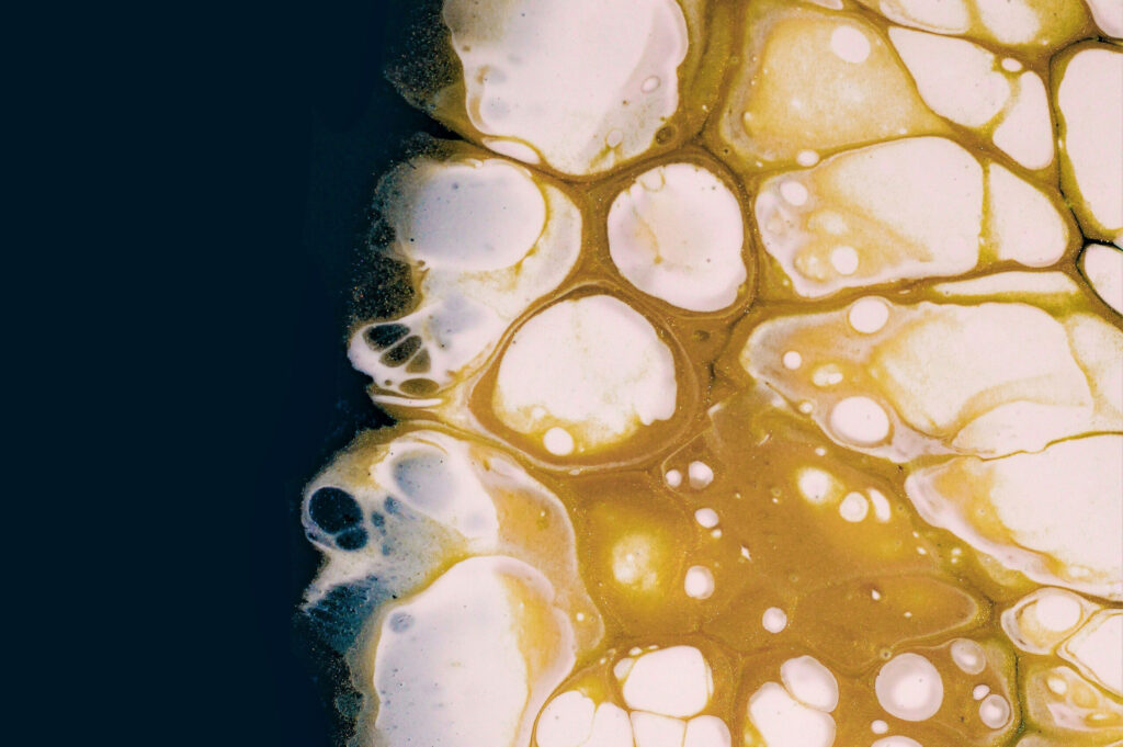A close up of a yellow, white, and blue substance in water